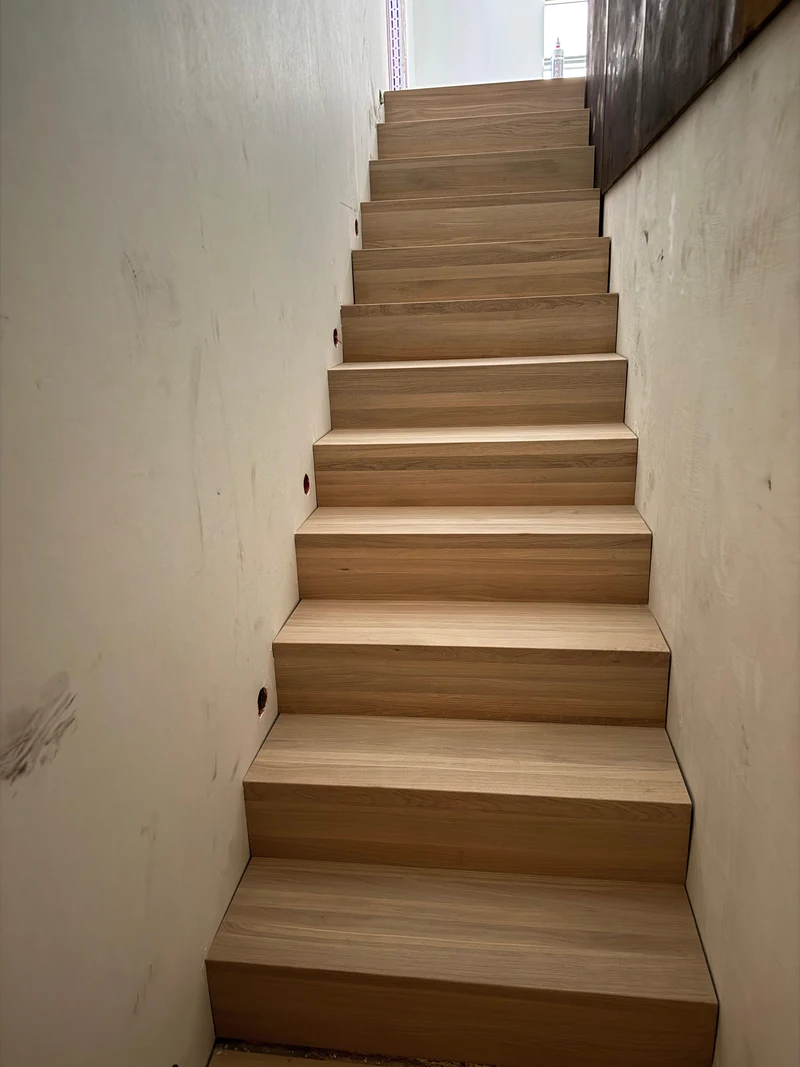 Massivholztreppe aus Eiche während der Montage, vom unteren Treppenabsatz aus gesehen