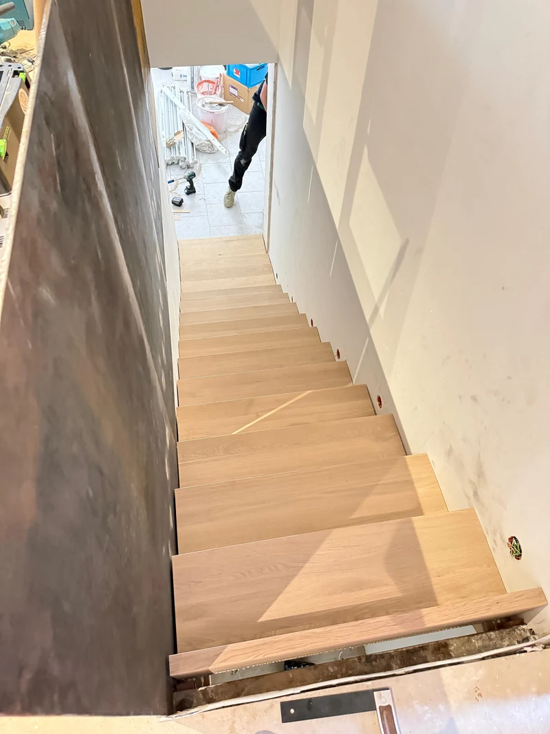 Blick vom oberen Treppenabsatz auf die Massivholztreppe aus Eiche während der Montage