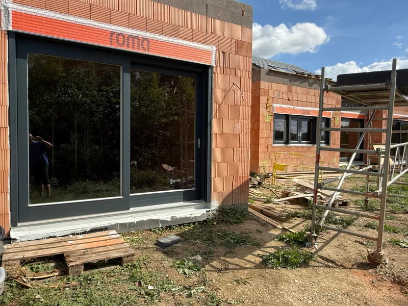 Außenansicht eines anthrazitgrau lackierten Holz-Schiebeelements mit Aufsatzrollladen während der Bauphase