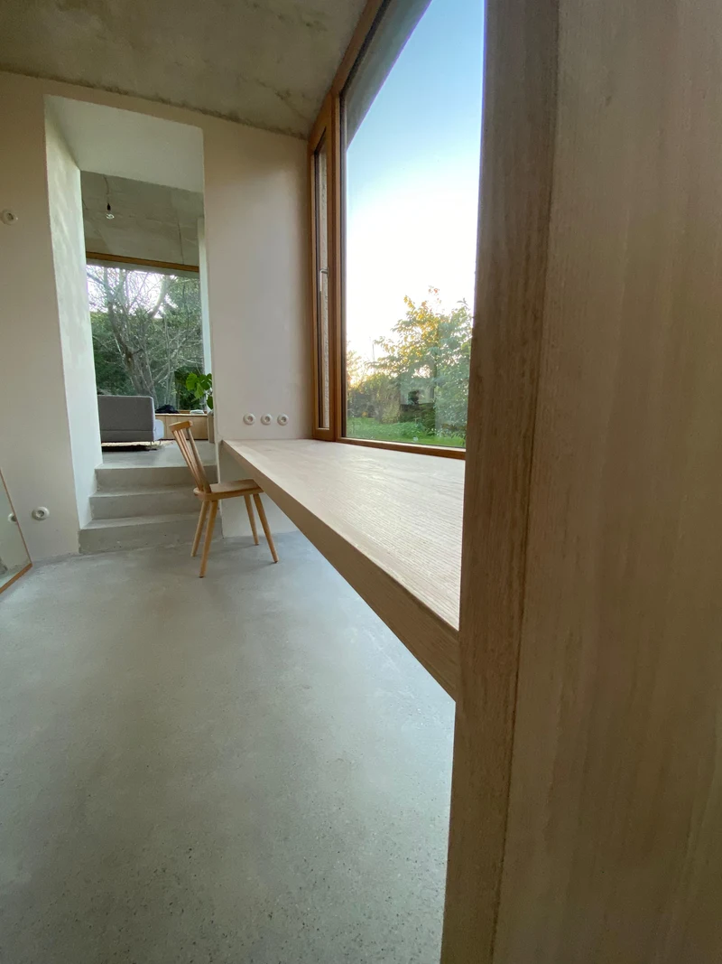 Seitliche Ansicht des Schreibtischs an der Fensterfront mit Holzverkleidung und Blick in den Garten