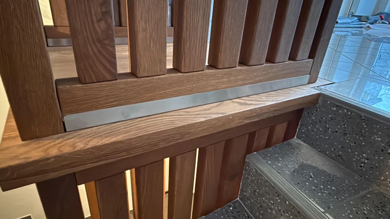 Detail der Eichenlamellen mit sichtbarer Maserung und Anschluss an die Steintreppe