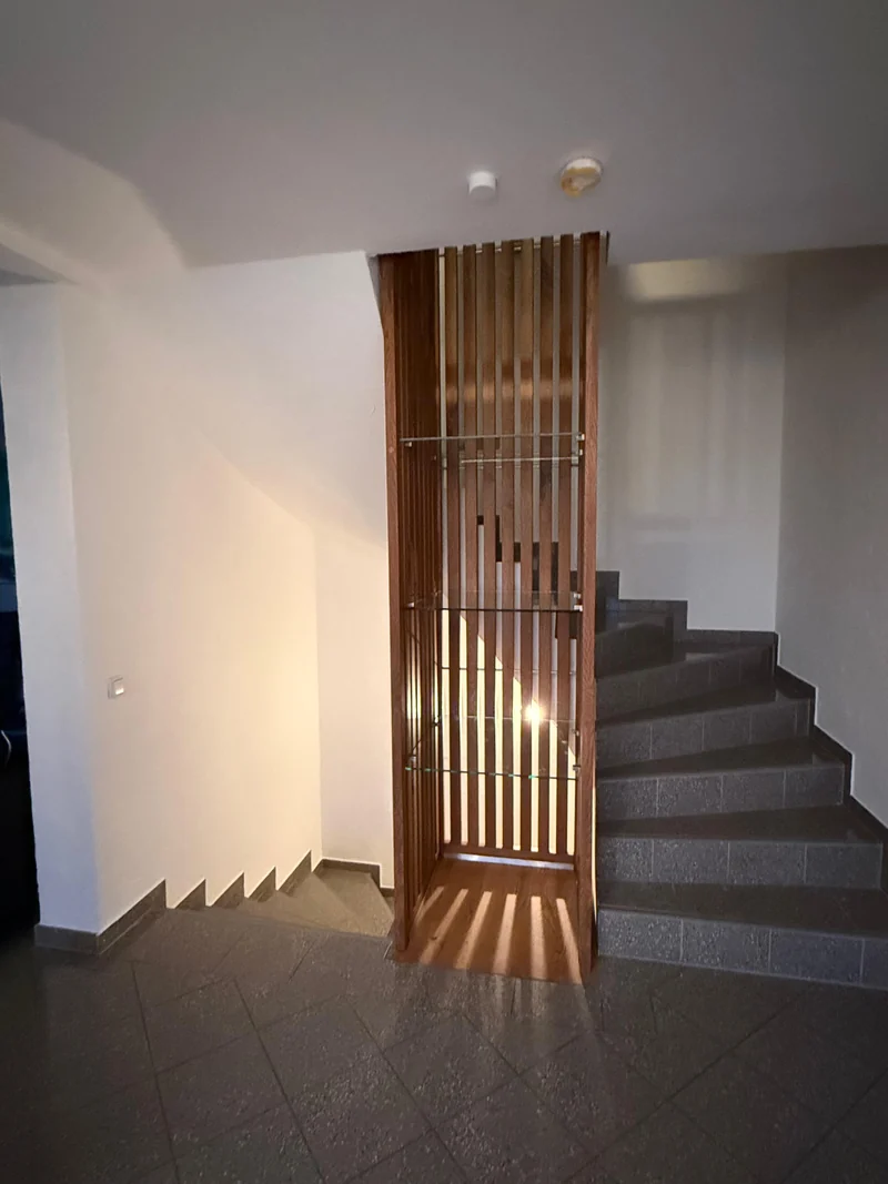 Treppenhaus mit raumhohen Eichenlamellen, Glasböden und seitlicher Steintreppe